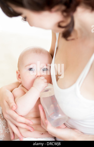 Mutter füttert ihr kleines Mädchen aus Flasche Stockfoto