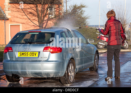 Frau Waschen Auto mit Jet Wash spray Stockfoto