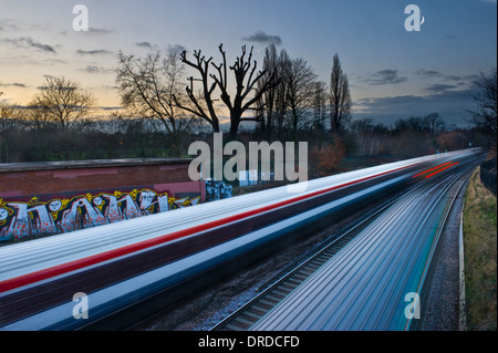 Ein Zug blinkt von einer Mauer Graffiti bedeckt mit Neumond im Hintergrund Stockfoto