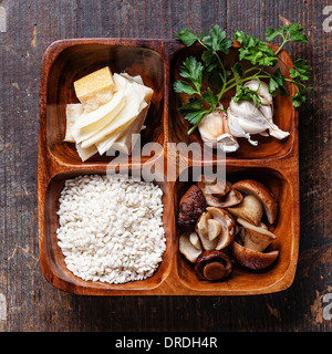 Roher Reis in Holzschale mit Zutaten für Risotto mit Steinpilzen Stockfoto