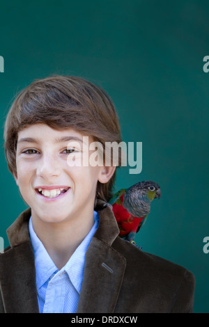 Junge mit Papagei auf der Schulter Stockfoto