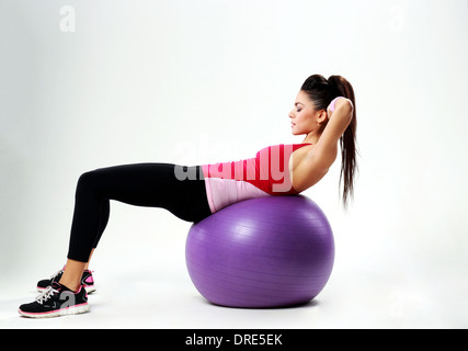 Junge sport Frau tut abs Workout auf Fitball über grauen Hintergrund Stockfoto
