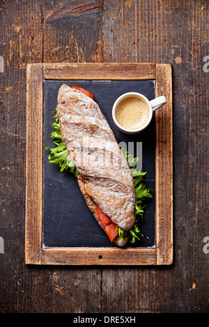 Sandwich mit geräuchertem Lachs und Kaffee auf Vintage Schiefer Kreide Board Hintergrund Stockfoto