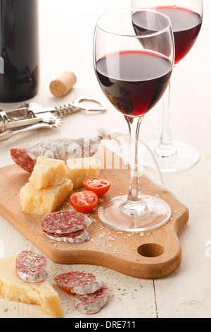 Zwei Weingläser mit Rotwein und Auswahl an Käse und Früchte auf weißem Hintergrund Stockfoto