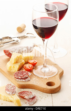 Zwei Weingläser mit Rotwein und Auswahl an Käse und Früchte auf weißem Hintergrund Stockfoto