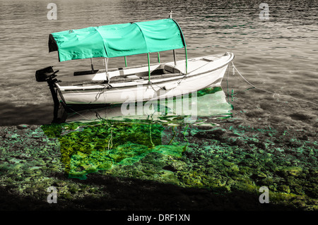 kleines Fischerboot mit Bimini. Verankerung im klaren flachen Wasser. Das Boot ist im Wasser spiegelt. Stockfoto