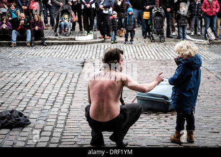 A Street Performer und ein kleiner Junge eine Menschenmenge in Covent Garden Piazza unterhaltsam. Stockfoto