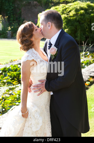 Glücklich Hochzeitspaar küssen in schönen Garten in Sonnenschein Stockfoto