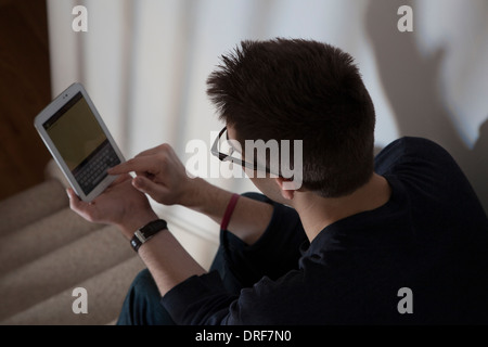 Über Schulter Schuss von Mann mit Brille, die Eingabe über eine Tastatur auf dem Touch-Bildschirm digitale Tablett. Stockfoto