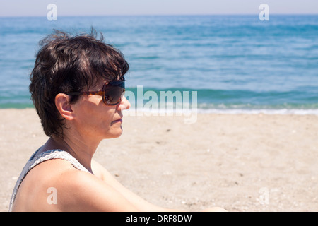 Porträt von glücklich mittlere gealterte Frau entspannend am Strand. Stockfoto