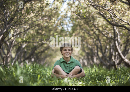 Utah USA Junge sitzt mit gekreuzten Beinen Wald Tunnel von Bäumen Stockfoto