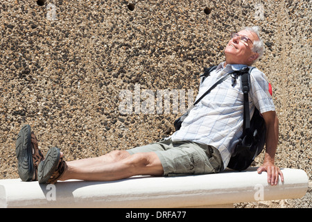 Senior woman Backpacker ruht auf Bank im Freien an sonnigen Tag Stockfoto