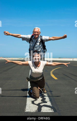 Happy senior woman und Mitte im Alter Frau imitieren Flugzeug auf der Landebahn des Flughafens Stockfoto