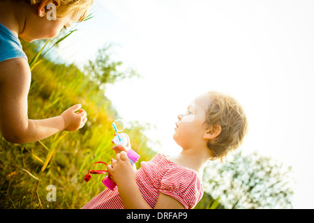 Zwei Kinder bläst Seifenblasen im Freien, Bayern, Deutschland Stockfoto