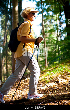 Ältere Frau Nordic Walking durch Wald, Osterseen, Deutschland Stockfoto