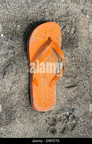 Orange Flip-flop am Sandstrand. Stockfoto