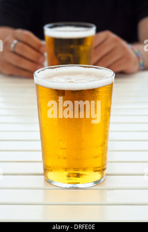 Nahaufnahme von Glas frisches Bier und die Hände auf den Tisch. Stockfoto