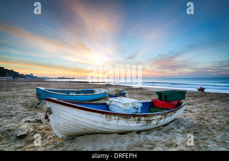 Angelboote/Fischerboote am Strand bei Sonnenaufgang am Strand von Bournemouth mit Mole in weiter Ferne Stockfoto