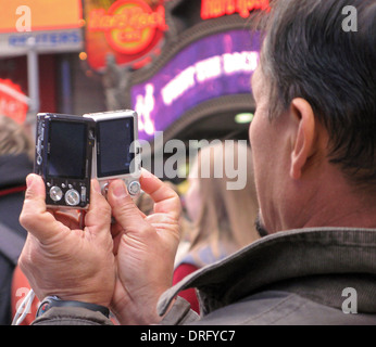 Ein Tourist in der Times Square, die Teil von Manhattan, New York nimmt Fotos mit zwei point and shoot-Kameras. Stockfoto