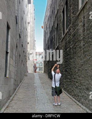 Ein Tourist im alten Teil der Stadt von Montreal Kanada nimmt ein Foto in einer schmalen Gasse Stockfoto