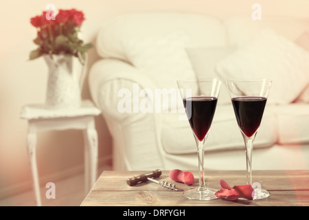 Gläser Rotwein mit Vase mit roten Rosen im Hintergrund Stockfoto