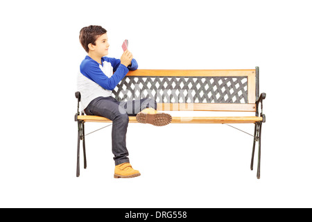 Kleiner Junge sitzt auf einer Holzbank und Spielkarten mit imaginären Freund Stockfoto