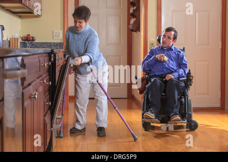 Mann und Frau mit zerebraler Lähmung Mittagessen vorbereiten und verwenden den Geschirrspüler in ihrer Küche zu Hause Stockfoto