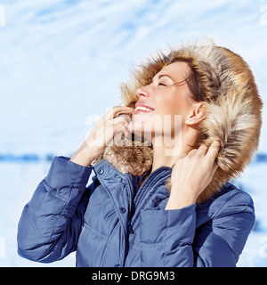 Closeup Portrait glücklich Frau mit geschlossenen Augen genießen Sonne Licht im kalten frostigen Tag tragen modische Winter Kleidung Stockfoto