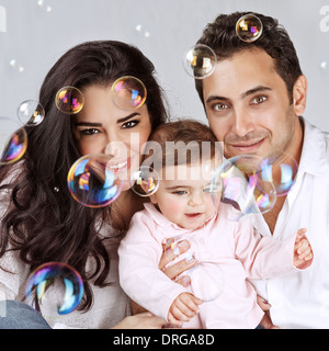 Closeup Portrait der niedliche kleine Baby-Mädchen mit schönen Eltern genießen Seifenblasen, spielen mit Luftblasen Wasser, glückliche Kindheit Stockfoto