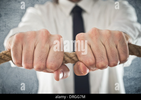 Unternehmer, die an einem Seil festhalten. Konzept der Geschäftsprobleme, schwierigen Geschäftslage. Stockfoto