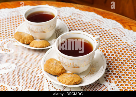 Zwei volle Teetassen mit Keksen, Vintage Dekor mit antiken Teeservice mit Gold, Spitzen und Eiche Tisch Stockfoto