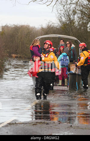 Muchelney, Somerset, UK. 25. Januar 2014. Ein Feuerwehrmann aus Devon & Somerset Feuerwehr und Rettungsdienst trägt ein junges Mädchen aus der humanitären Fähre zurück zum Festland in Muchelney. Das Dorf hat seit Anfang Januar 2104 abgeschnitten worden. Stockfoto