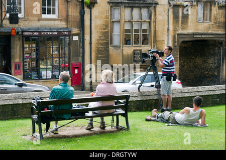 Paar auf einer Bank sitzen zwei junge Männer, die Dreharbeiten in Chipping Campden Warwickshire UK. Stockfoto