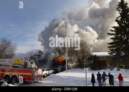 Familie draußen in der Nacht Kleidung während Haus in Flammen, mit Feuerwehr Aufsprühen von Wasser aufgeht auf Feuer und Rauch gießen von zu Hause in Ottawa Kanada Stockfoto