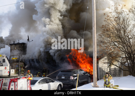 Feuerwehrleute kämpfen um knock down ein loderndes strukturelle Haus Feuer im Winter mit Flammen und Rauch Ottawa Kanada Stockfoto