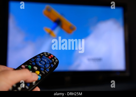 Menschen, die auf eine universelle Fernbedienung auf einem TV-Bildschirm das Programm auf dem Entertainment System zu ändern. Stockfoto