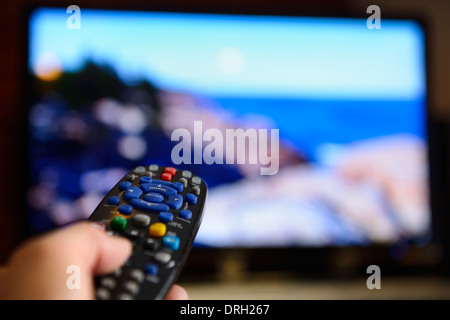 Person zeigt eine universale-Fernbedienung auf ein TV-Bildschirm-Entertainment-system Stockfoto