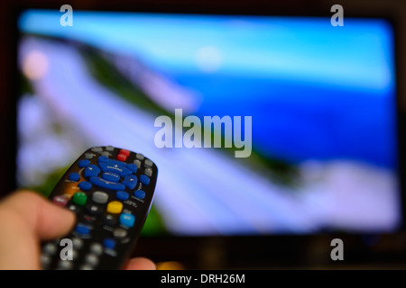 Person zeigen Sie mit der Fernbedienung auf einem TV-Bildschirm zu Hause Stockfoto