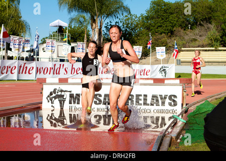 Weibliche Athleten in den Wassergraben beim Hindernislauf bei einem amerikanischen Leichtathletik Treffen in Kalifornien Stockfoto