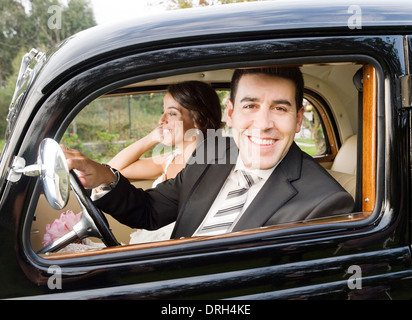 Ehepaar in einem alten Auto. Der Mann ist aus dem Fenster gelehnt. Stockfoto