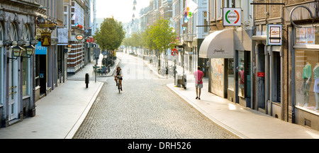 Maastricht sehr früh morgens ruhig von Bäumen gesäumte saubere Einkaufsstraße Straße & Gehwege ein Fußgänger und ein Radfahrer in Limburg Niederlande Europa Stockfoto