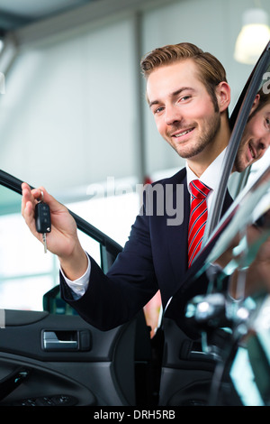 Verkäufer oder Auto Verkäufer im Autohaus mit Schlüssel präsentiert seine neue und gebrauchte Autos im showroom Stockfoto