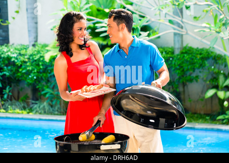 Asiatische hübsches Paar, Grillparty oder Grill draußen am Pool mit gegrillten Maiskolben Stockfoto