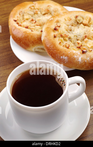 Tasse Kaffee und Runde Brötchen mit Apfel auf Tisch Stockfoto