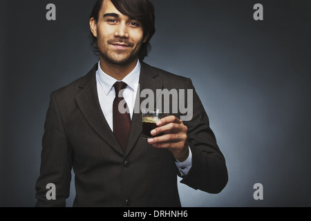 Porträt der glückliche junge Geschäftsmann bietet Ihnen eine Tasse Kaffee auf schwarzem Hintergrund. Gemischte Rassen Männermodel Stockfoto