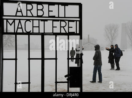 Oranienburg, Deutschland. 27. Januar 2014. Besuchern steht hinter dem Tor mit dem Schriftzug "Arbeit macht (Sie) frei" in der Gedenkstätte des KZ Sachsenhausen in Oranienburg, Deutschland, 27. Januar 2014. Der Opfer des Nationalsozialismus wurden mit der Verlegung der Kränze in Sachsenhausen anlässlich des Tages des Gedenkens an die Opfer des Nationalsozialismus gedacht. Foto: BERND SETTNIK/Dpa/Alamy Live News Stockfoto