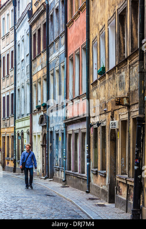 Ein junger Mann geht entlang einer engen, gepflasterten Seitenstraße in der Breslauer Altstadt. Stockfoto