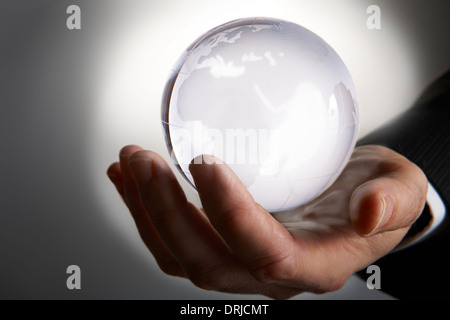 Unternehmenshilfe Hand mit glühenden Glaskugel in Palm vor grauem Hintergrund Stockfoto