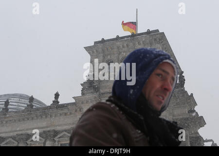 Berlin, Deutschland. 27. Januar 2014. Ein Tourist geht vorbei an Deutschlands Reichstagsgebäude auf die deutsche Flagge Halbmast in Berlin, Hauptstadt Deutschlands, am 27. Januar 2014 festgelegt ist. Am 27. Januar 1945 befreiten sowjetische Truppen Auschwitz, das größte nationalsozialistische Konzentrationslager in Polen, wo mehr als 1 Million Menschen getötet wurden. Im Jahr 2005 bezeichneten die Vereinten Nationen am selben Tag als internationalen Holocaust-Gedenktag zur Erinnerung an die Opfer des Holocaust. Bildnachweis: Zhang Fan/Xinhua/Alamy Live-Nachrichten Stockfoto