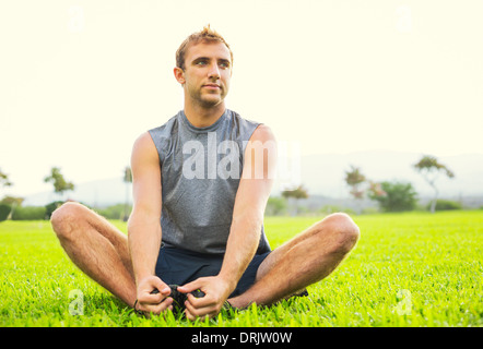 Attraktive Fit junger Mann stretching vor dem Training, Sonnenaufgang am frühen Morgen Hintergrundbeleuchtung. Gesunde Lebensweise-Sport-Fitness-Konzept. Stockfoto